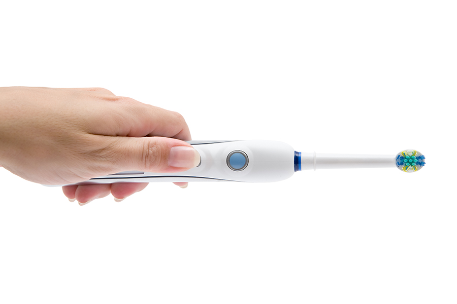 A hand holding an electric toothbrush