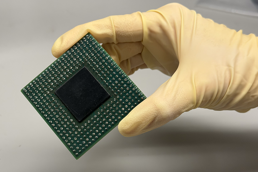 A gloved hand holding a computer chip